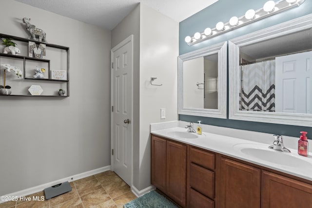 full bath featuring baseboards, a sink, and double vanity