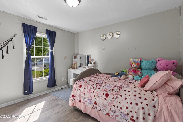 bedroom featuring baseboards, visible vents, and wood finished floors