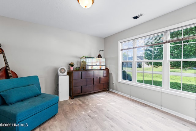living area featuring baseboards, visible vents, and wood finished floors