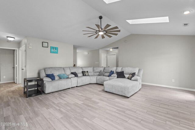 living area featuring ceiling fan, light wood-style flooring, baseboards, visible vents, and lofted ceiling with skylight