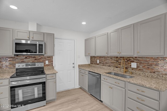 811 Crawford St, Goldsboro, NC 27530 - kitchen with light stone counters, appliances with stainless steel finishes, a sink, light wood-style floors, and tasteful backsplash