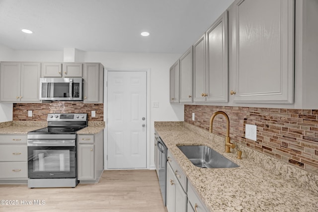 811 Crawford St, Goldsboro, NC 27530 - kitchen with light stone counters, a sink, light wood-style flooring, stainless steel appliances, and tasteful backsplash
