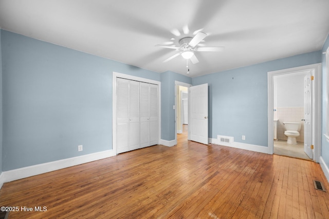 unfurnished bedroom featuring baseboards, wood-type flooring, a closet, and visible vents