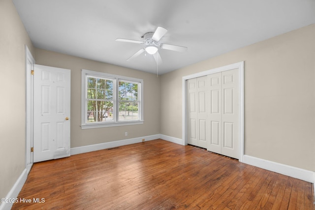 unfurnished bedroom featuring a ceiling fan, visible vents, baseboards, wood-type flooring, and a closet