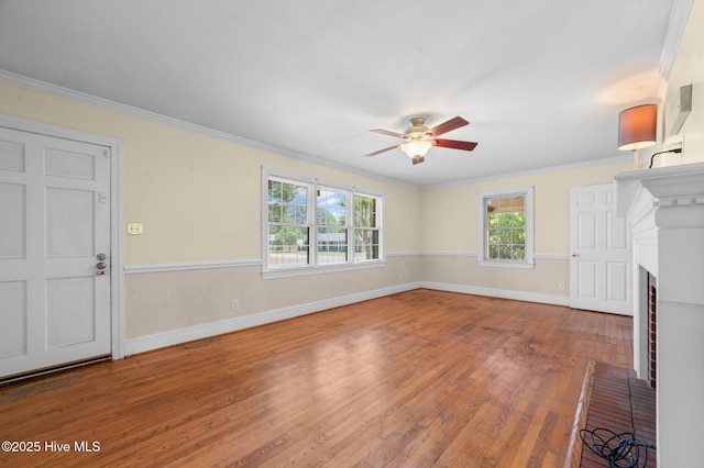 unfurnished living room with crown molding, a fireplace, a ceiling fan, baseboards, and wood finished floors