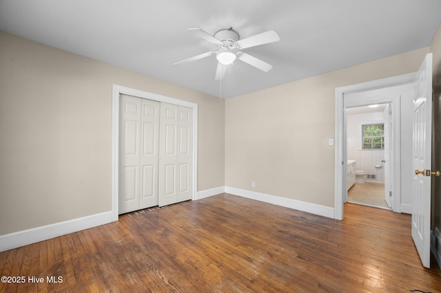 unfurnished bedroom with a closet, baseboards, a ceiling fan, and hardwood / wood-style floors