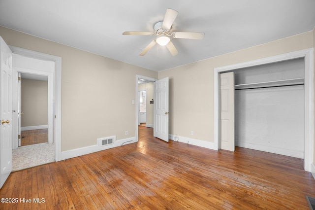 unfurnished bedroom with ceiling fan, baseboards, visible vents, hardwood / wood-style flooring, and a closet