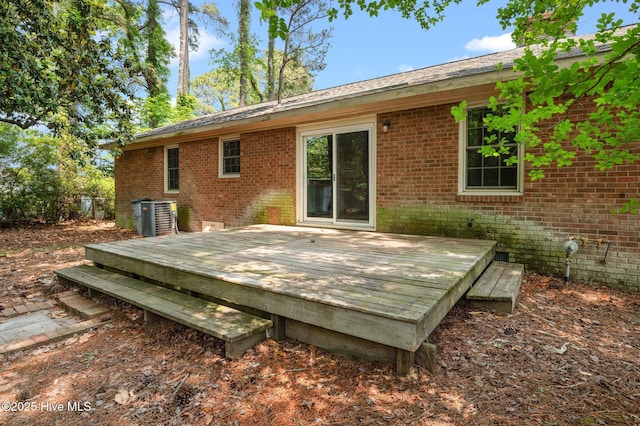rear view of house featuring brick siding, central AC unit, and a deck
