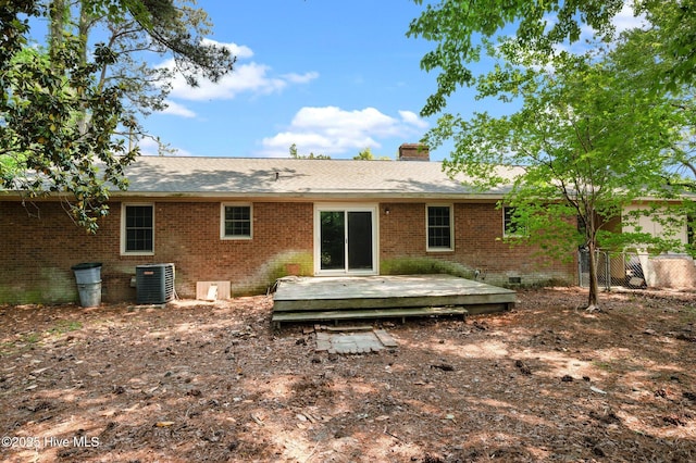 back of property featuring crawl space, a chimney, a deck, brick siding, and central AC