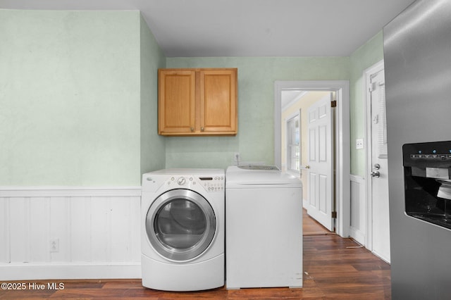 clothes washing area featuring a wainscoted wall, dark wood-type flooring, cabinet space, and washing machine and clothes dryer