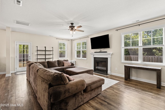 living area with plenty of natural light, ceiling fan, wood finished floors, and visible vents