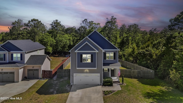 traditional-style house with fence, driveway, a front yard, and a garage