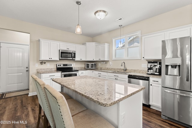 kitchen with visible vents, pendant lighting, a kitchen breakfast bar, white cabinets, and stainless steel appliances