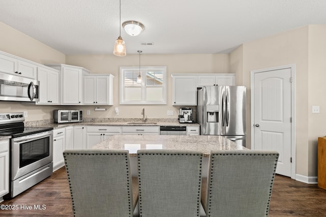 kitchen with a kitchen island, white cabinetry, appliances with stainless steel finishes, and a sink