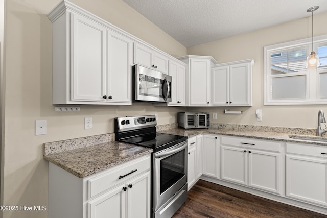 kitchen featuring white cabinets, appliances with stainless steel finishes, a sink, and dark wood-type flooring