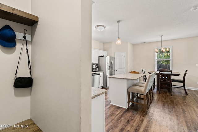 kitchen featuring dark wood-style flooring, a kitchen bar, a center island, white cabinets, and stainless steel appliances