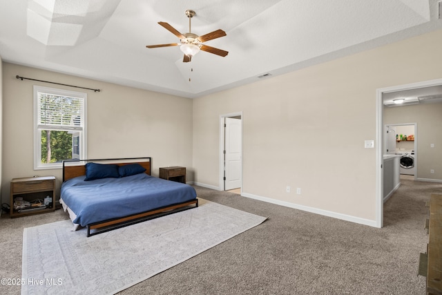 carpeted bedroom with visible vents, baseboards, a tray ceiling, and washer / dryer