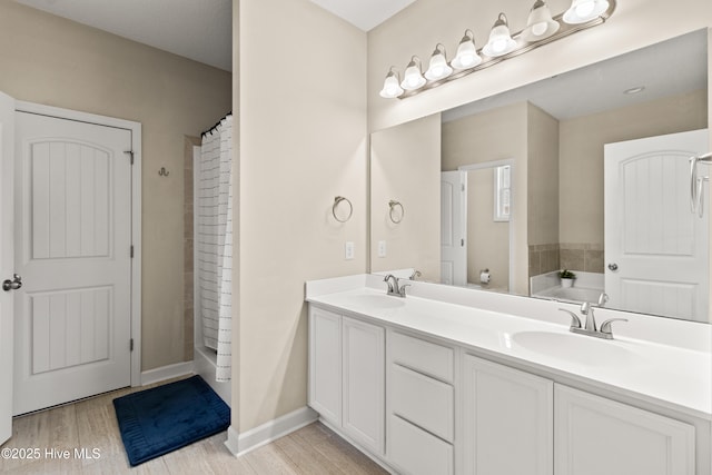 full bath featuring double vanity, a sink, wood finished floors, and a tub