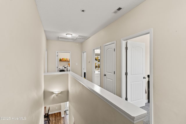 hallway featuring visible vents, baseboards, independent washer and dryer, and wood finished floors