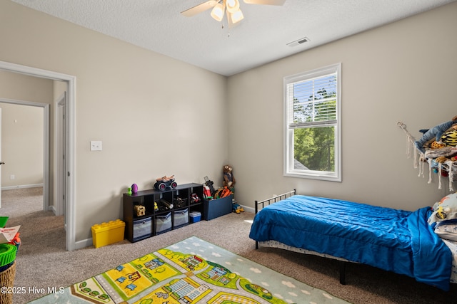 carpeted bedroom with baseboards, ceiling fan, a textured ceiling, and visible vents