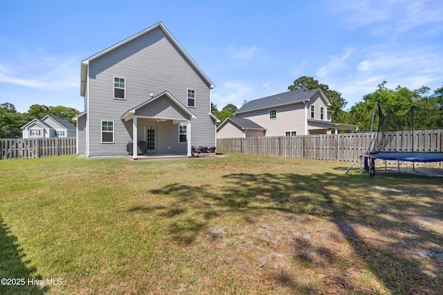 rear view of property with a patio, a fenced backyard, a trampoline, and a lawn