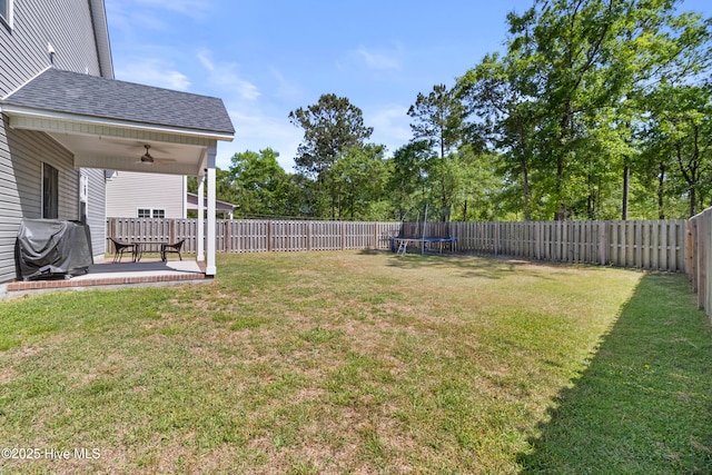view of yard featuring a ceiling fan, a trampoline, and a fenced backyard
