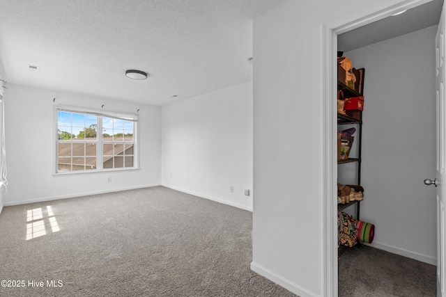 carpeted empty room with baseboards and a textured ceiling
