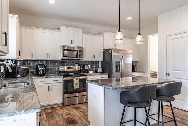 kitchen featuring a kitchen breakfast bar, a center island, white cabinetry, a sink, and stainless steel appliances
