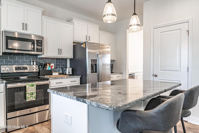 kitchen featuring white cabinets, a breakfast bar area, a center island, stainless steel appliances, and tasteful backsplash
