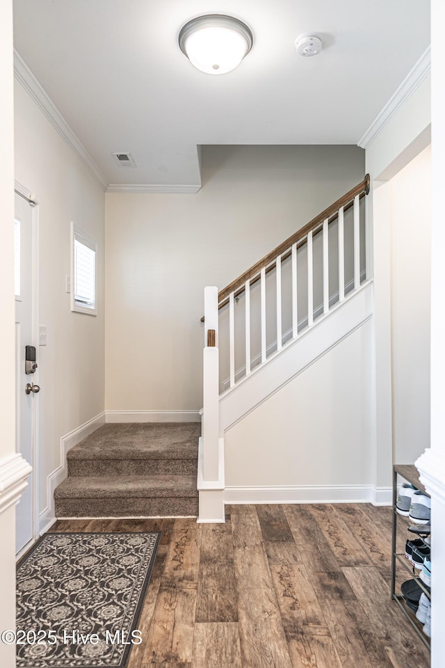 stairs featuring baseboards, ornamental molding, wood finished floors, and visible vents