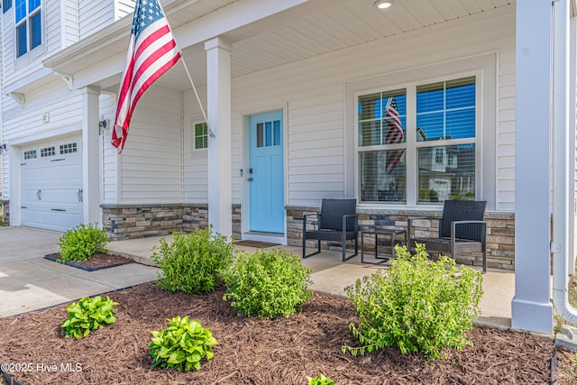 property entrance with covered porch, an attached garage, and stone siding