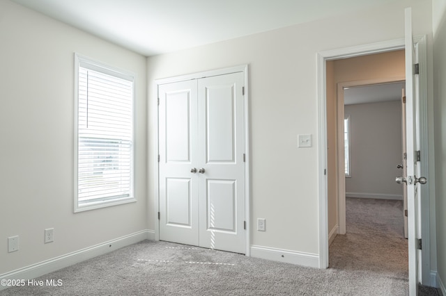 unfurnished bedroom with carpet flooring, baseboards, multiple windows, and a closet