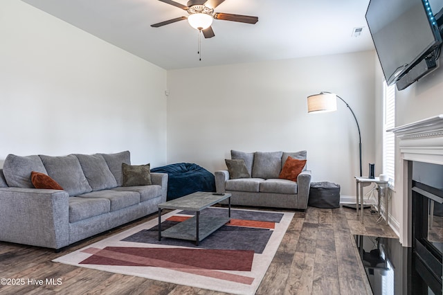living area with a ceiling fan, visible vents, wood finished floors, and a fireplace
