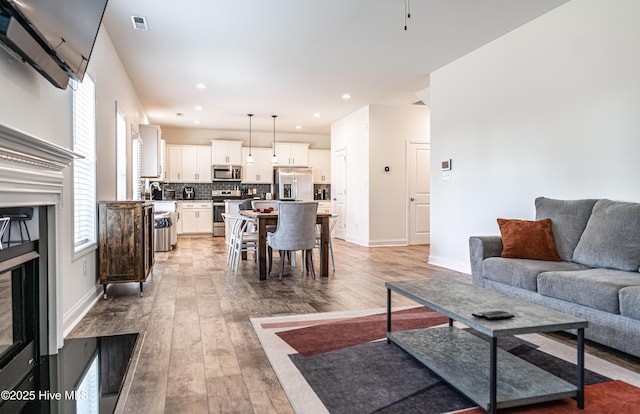 living room featuring a healthy amount of sunlight, baseboards, light wood-type flooring, and visible vents