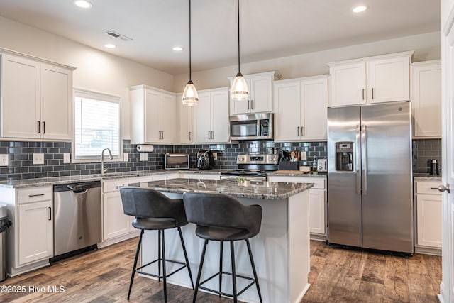kitchen with a sink, appliances with stainless steel finishes, a breakfast bar, and wood finished floors