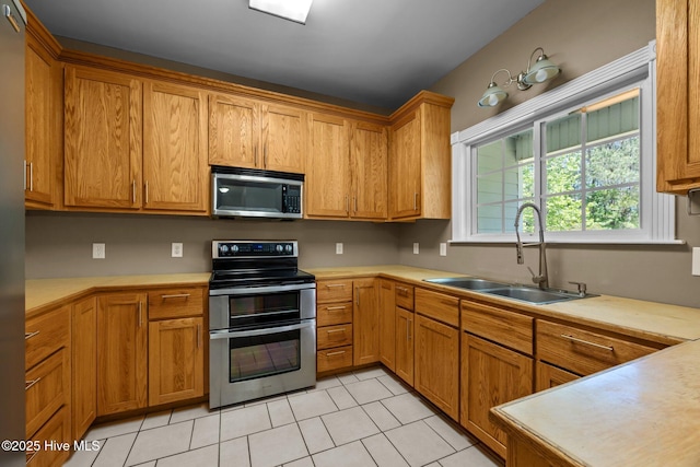 kitchen featuring light countertops, a sink, light tile patterned floors, and stainless steel appliances