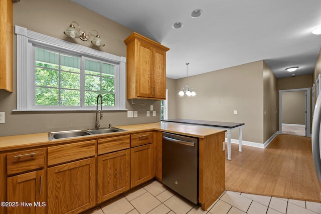 kitchen featuring a peninsula, light countertops, brown cabinets, a sink, and dishwasher