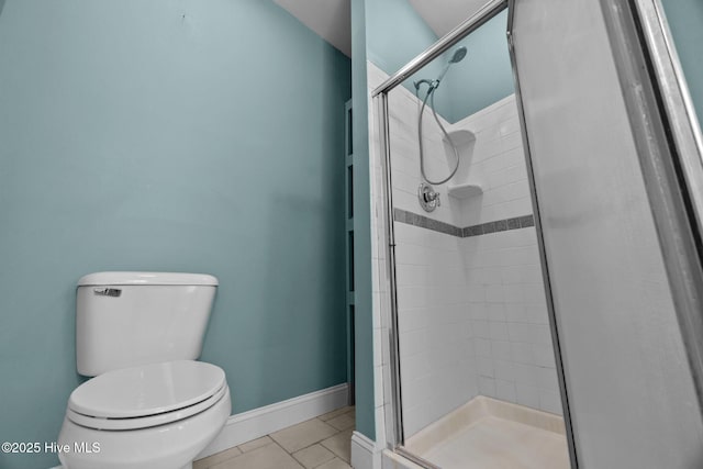 bathroom featuring toilet, tile patterned floors, baseboards, and a stall shower