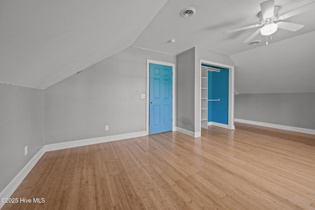 additional living space with light wood-style floors, a ceiling fan, lofted ceiling, and visible vents