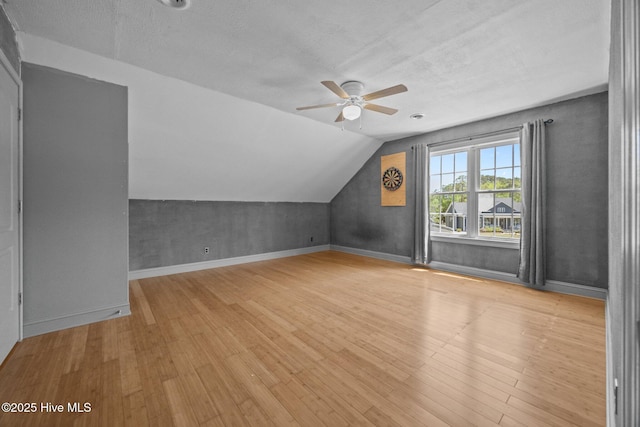 bonus room featuring a textured ceiling, ceiling fan, vaulted ceiling, and wood finished floors