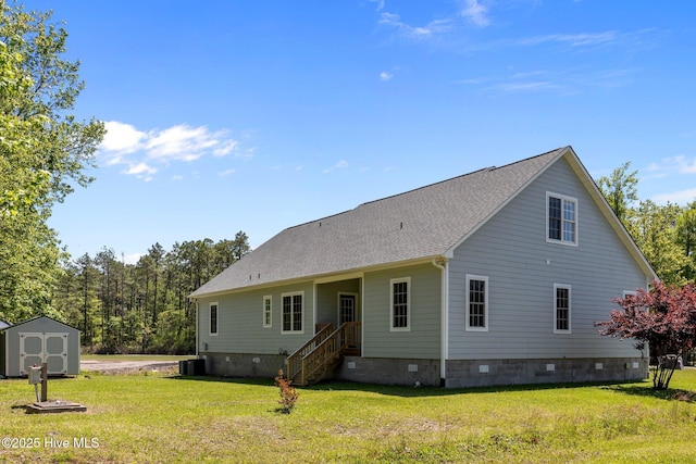 back of property with a lawn, a storage unit, an outbuilding, and crawl space