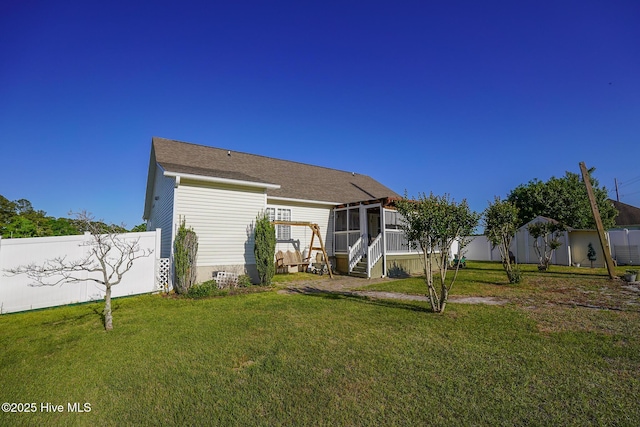 rear view of property featuring a lawn, fence, and a sunroom