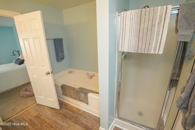 ensuite bathroom featuring a bath, a shower stall, wood finished floors, and connected bathroom