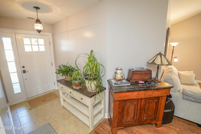 entrance foyer featuring baseboards, light tile patterned flooring, and visible vents