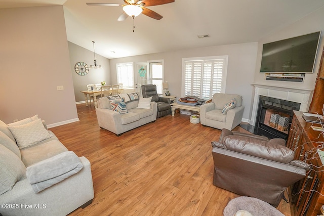 living area featuring a ceiling fan, visible vents, a fireplace, lofted ceiling, and light wood-style floors