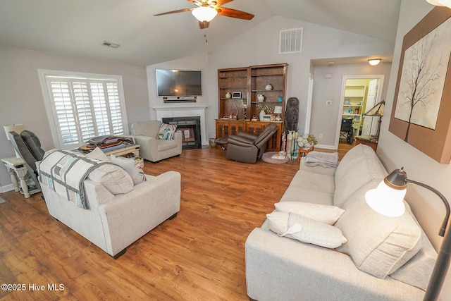 living area featuring a ceiling fan, visible vents, light wood finished floors, and vaulted ceiling