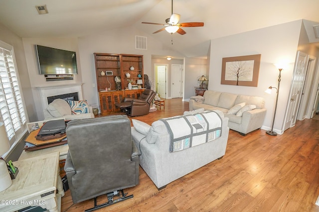 living area with ceiling fan, visible vents, vaulted ceiling, and light wood finished floors