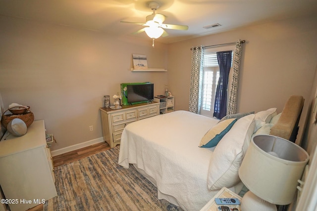 bedroom featuring visible vents, baseboards, ceiling fan, and wood finished floors