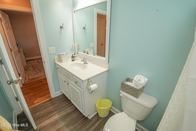 bathroom featuring vanity, baseboards, wood finished floors, and toilet
