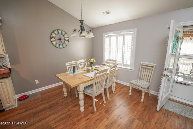 dining room featuring a chandelier, baseboards, wood finished floors, lofted ceiling, and visible vents